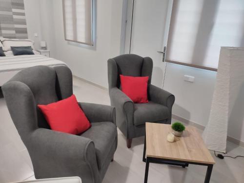 a bedroom with two chairs and a bed with red pillows at Apartamento Madrid Norte in Madrid