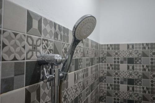 a shower with a mirror on a tiled wall at KoolKost Syariah At Laweyan Solo in Solo