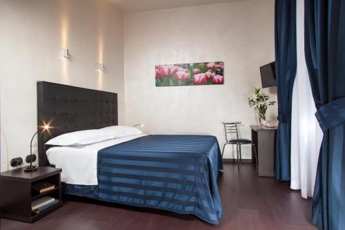ein Schlafzimmer mit einem Bett mit einer blauen Decke und Blumen in der Unterkunft Residenza Dorò- 24x7 Check-in in Rom