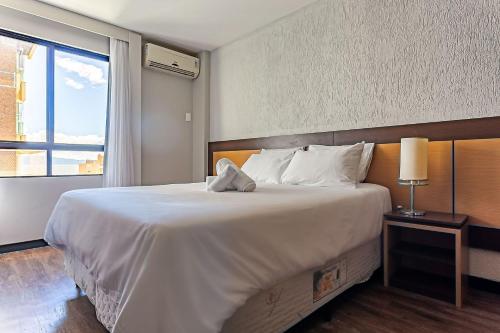um quarto com uma grande cama branca e uma janela em Piscina no Rooftop com Vista Ponte e Mar #CA22 em Florianópolis