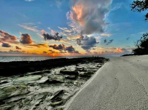 a beach with a cloudy sky and the sunset at Thoddoo Island Life in Thoddoo