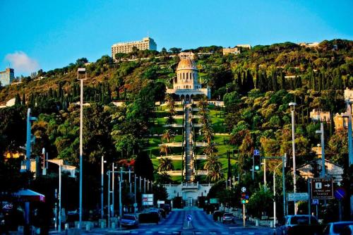 a building on top of a hill with cars on a street at יחידות אירוח נוף המפרץ in Haifa