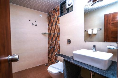 une salle de bain avec un lavabo, des toilettes et un miroir dans l'établissement Grande Ave Maria Resort, à Candolim