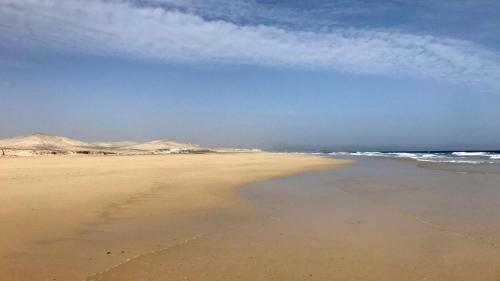 a beach with the ocean and mountains in the background at Rio Sol - Oasis de Privacidad in Costa Calma