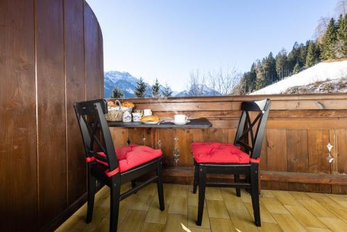 two chairs with red cushions sitting on a porch at KASSNHOF - Urlaub in den Bergen in Telfes im Stubai