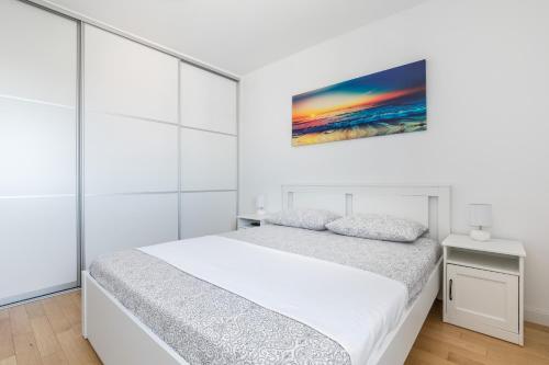 a white bedroom with a bed and a painting on the wall at Diva apartment with free private parking in Split