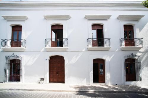 un edificio blanco con puertas y ventanas marrones en Pug Seal Oaxaca, en Oaxaca City