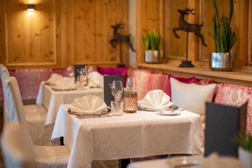 a restaurant with two tables with white tablecloths and napkins at Superior Sport und Familienresort Alpenblick in Zell am See