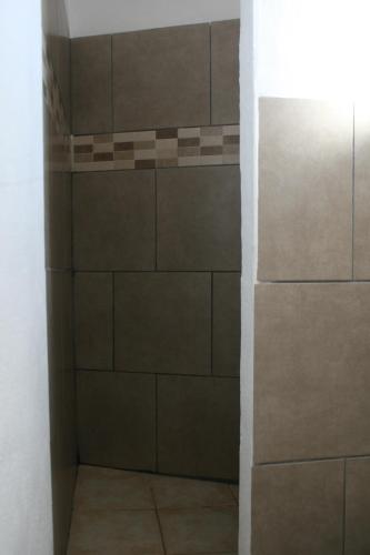 a bathroom with a white tile floor and a black wall at La Palma Hostel by Pension Central in Fuencaliente de la Palma