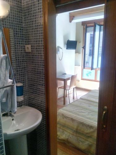 a bathroom with a sink and a bed and a table at ALBOR II in Gijón