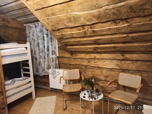 Tysovets的住宿－Сімейний Затишок Готель，一间卧室设有木墙、两把椅子和一张桌子