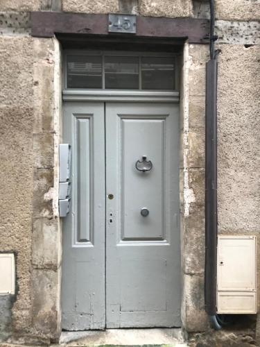 eine graue Tür in einem Backsteingebäude mit einem Fenster in der Unterkunft L'appart 45 in Rodez
