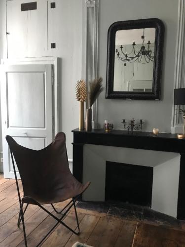 - une chaise dans le salon avec un miroir et une cheminée dans l'établissement L'appart 45, à Rodez