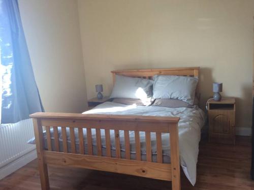 a wooden bed in a room with a window at Rossport bungalow with an Atlantic view in Ballina