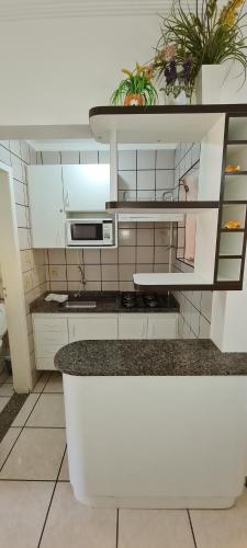 a kitchen with white cabinets and a counter with plants at diRoma Fiori - Apartamentos JN in Caldas Novas