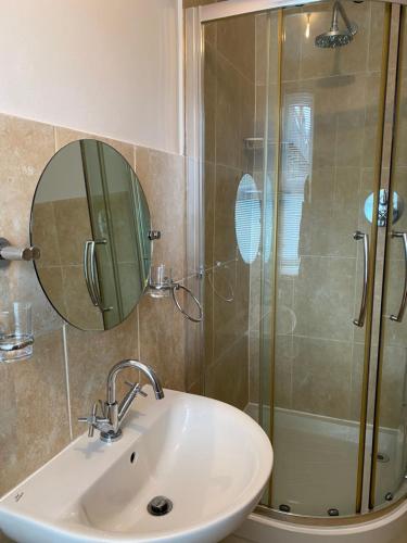 a bathroom with a sink and a shower with a mirror at Town House In The Heart of Pateley Bridge in Pateley Bridge