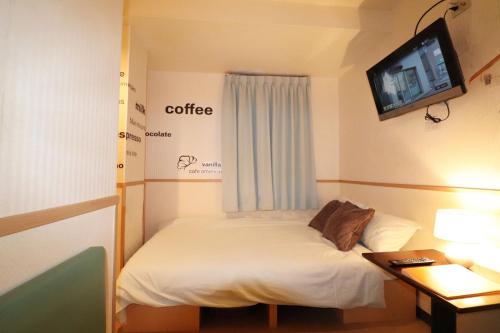 東京にあるHotel Yuyukan - Vacation STAY 10008vのベッド1台、壁掛けテレビが備わる小さな客室です。