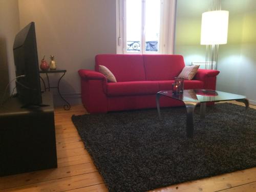 ein Wohnzimmer mit einem roten Sofa und einem Couchtisch in der Unterkunft GITE MAISON WEEK END in Dunkerque
