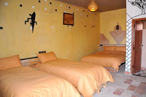 a bedroom with three beds in a room at Maison Acacias in Erfoud