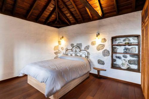ein Schlafzimmer mit einem Bett und einer Wand mit Steinen in der Unterkunft Casa Barreros in Arecida