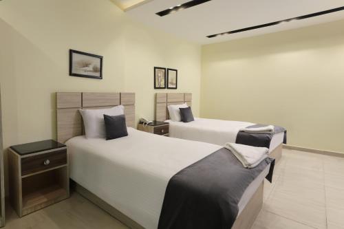 two beds in a room with white walls at Brothers Pyramids View in Cairo