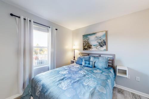 a bedroom with a blue bed and a window at Grand Caribbean #103 in Orange Beach