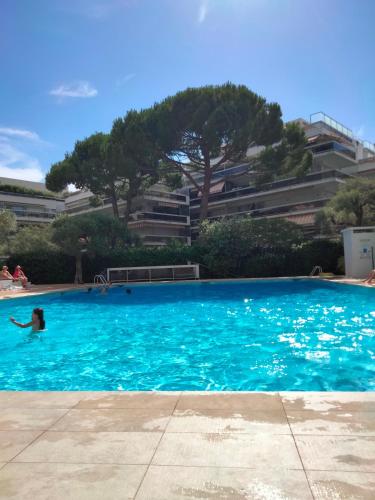 une personne nageant dans une grande piscine bleue dans l'établissement 10mm a pied des plages, appartement olympe climatisé, à Antibes