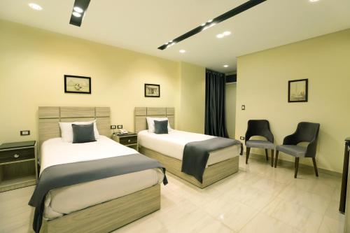 a hotel room with two beds and a chair at Brothers Pyramids View in Cairo