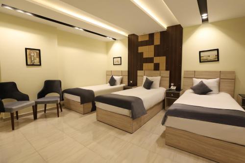 a hotel room with two beds and a chair at Brothers Pyramids View in Cairo