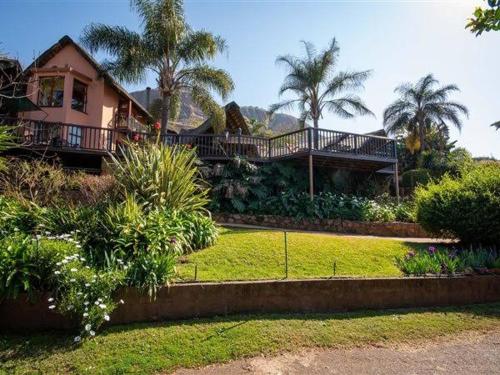 a house with a balcony and a yard with palm trees at Marina Views Guesthouse in Hartbeespoort
