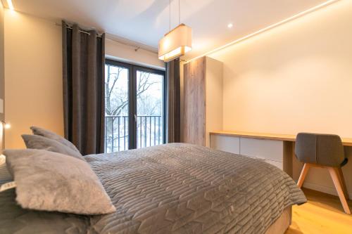 een slaapkamer met een bed, een bureau en een raam bij Luksusowy Apartament Enklawa pod Skrzycznem z sauną i bilardem - Dream Apart in Szczyrk
