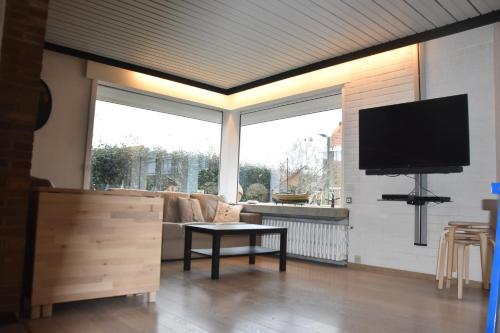 a living room with a television and a couch at 't Calmeyntje in De Panne