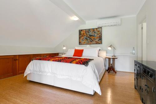 a white bedroom with a bed and a table at The Farm Willunga in Willunga