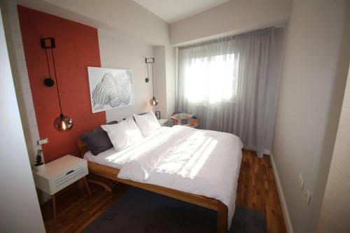 um quarto com uma grande cama branca e uma janela em Kristina's Cozy Designer Apartment em Skopje