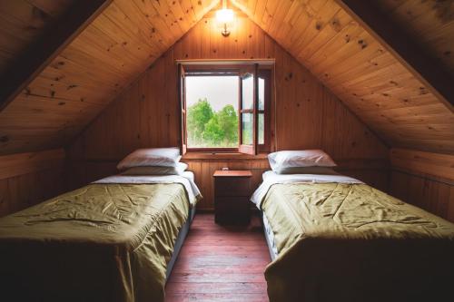 2 Betten in einem Dachzimmer mit Fenster in der Unterkunft Centro Los Alamos in Maldonado