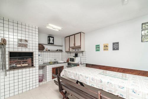 eine Küche mit weiß gefliesten Wänden und einer Holzbank in der Unterkunft Casa na praia de Morrinhos Bombinhas para 10 pessoas, Excelente localização in Bombinhas