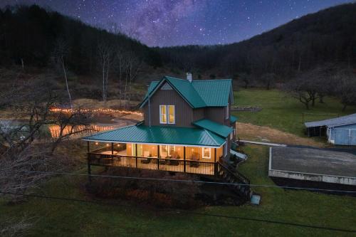 a house with a green roof in a field at night at The Olde Homestead with Mtn Views Near Coudersport in Coudersport