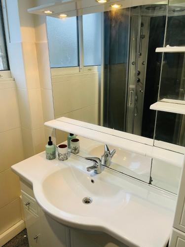 une salle de bain avec un lavabo blanc et un miroir dans l'établissement Charmant appartement de cœur de ville - 2 chambres lits Queen size - NETFLIX - WIFI, à Cherbourg en Cotentin