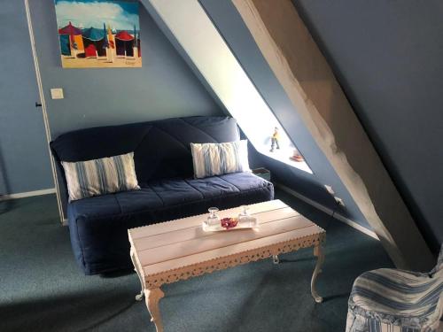 a living room with a blue couch and a table at Le Vieux Pressoir in Pont-lʼÉvêque