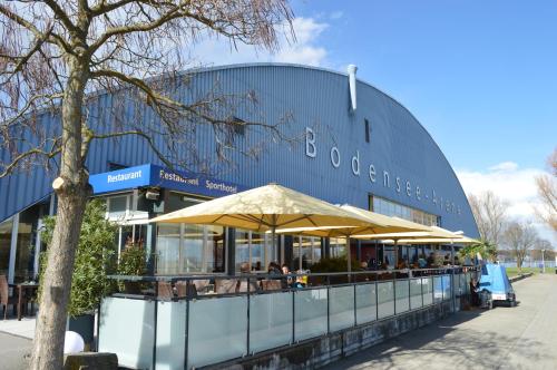 a restaurant with an umbrella in front of a building at Hotel Bodensee-Arena in Kreuzlingen