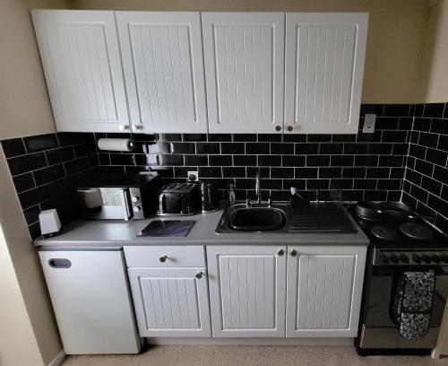 a kitchen with white cabinets and a sink at Sandy Beach Hill View Apartment Brean in Brean