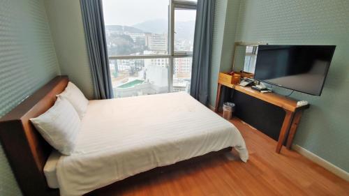 ein Hotelzimmer mit einem Bett und einem Flachbild-TV in der Unterkunft Myeongdong Merlin Hotel in Seoul