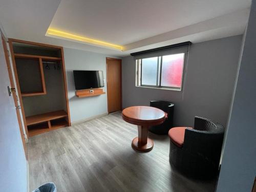 a room with a table and chairs and a television at Hotel El Senador in Mexico City
