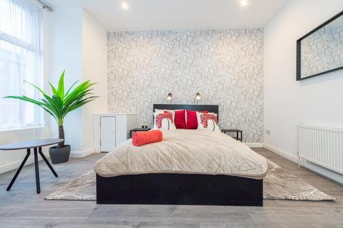 een slaapkamer met een bed met rode kussens en een tafel bij The Blossoms Studio Apartments in Liverpool