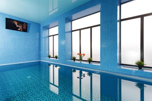 una piscina con azulejos azules y ventanas en DK Kompleks Hotel, en Novosibirsk