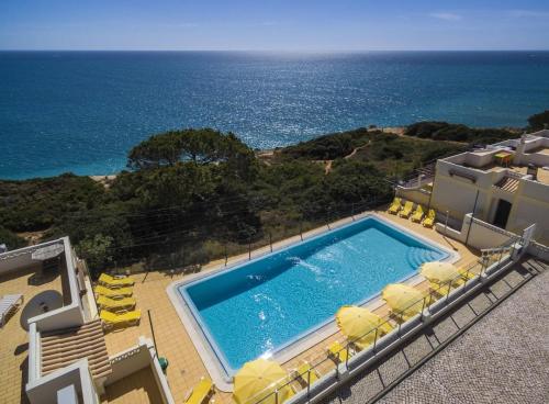 a swimming pool with chairs and the ocean in the background at Seaview Terrace Benagil Villa 45 in Benagil