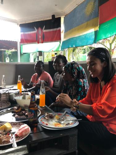 a group of people sitting at a table eating food at The Greenhouse Hostel Arusha Tanzania in Arusha