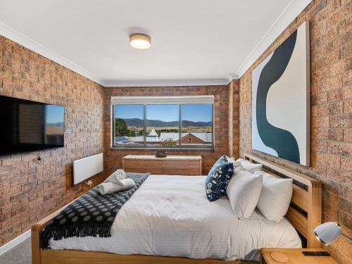 a bedroom with a bed and a brick wall at Astrids at Central Park in Jindabyne