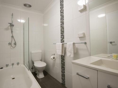 a white bathroom with a tub and a toilet and a sink at Astrids at Central Park in Jindabyne