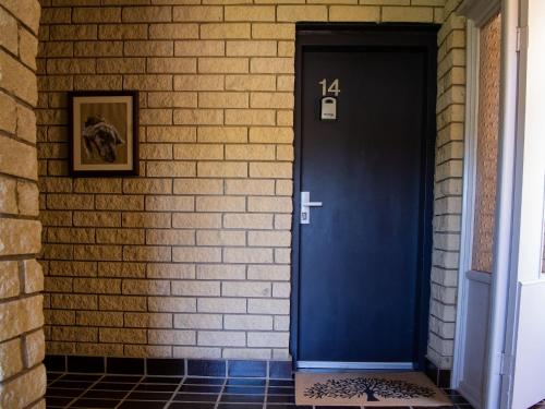 a blue door on a brick wall with a picture at Astrids at Central Park - 2BR l Lake & Mountain Views l Central Location l WiFi in Jindabyne